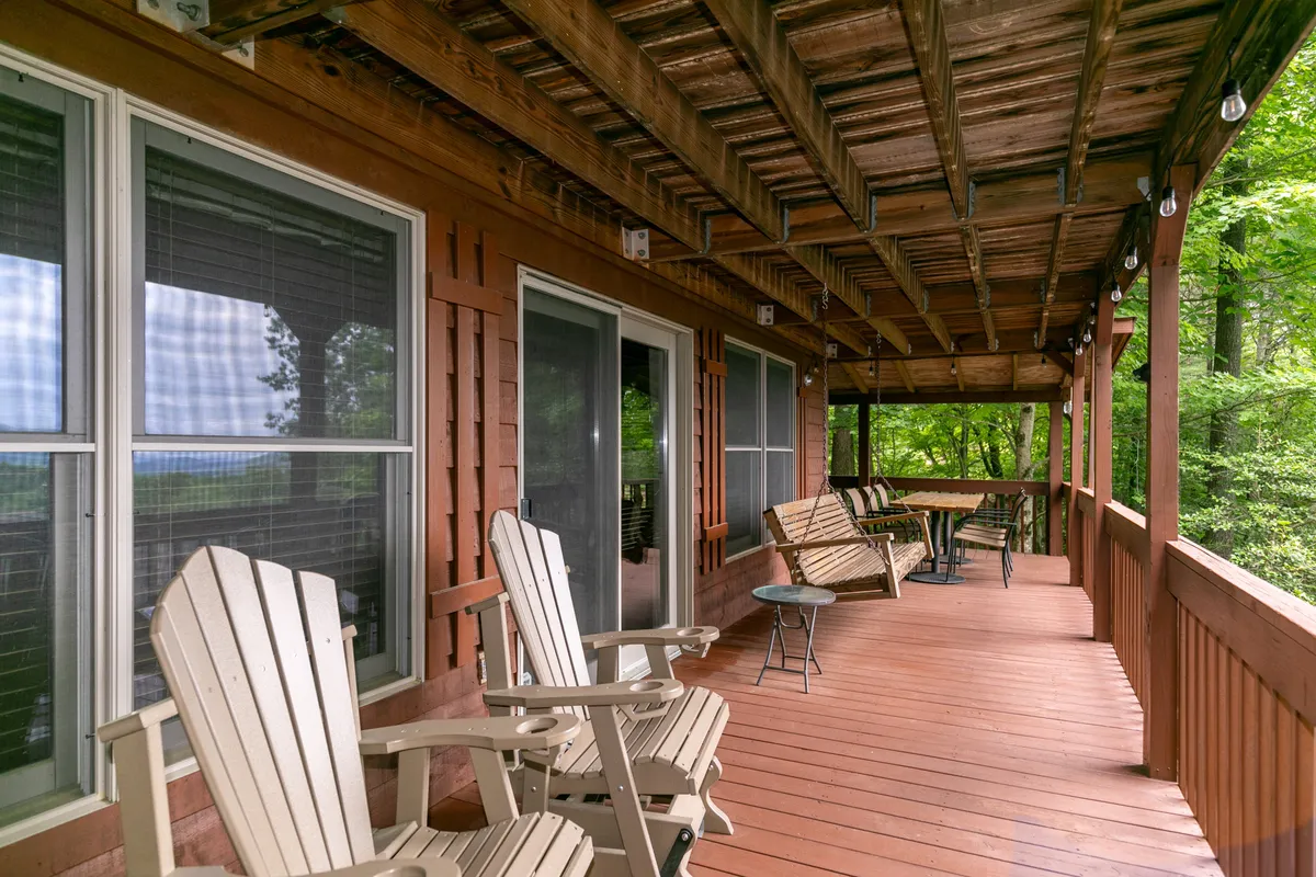 A tranquil exterior shot of wooden rocking chairs on the deck, facing natural scenery. The seating arrangement invites relaxation while connecting guests to the outdoors and the fenced yard area.